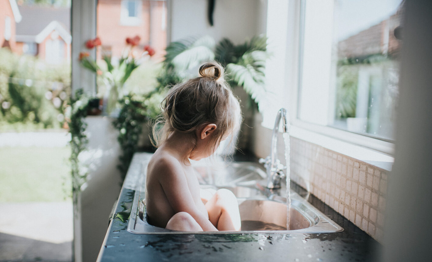Kleines Kind badet im Spuehlbecken